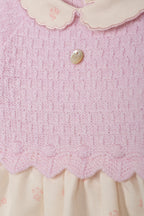 Detailopname roze gebreide stof, scallop-rand en parelmoer knopje babyjurk DK108