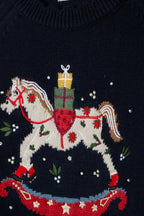 Detail van het hobbelpaard met cadeautjes, sterren en bloemdetails op de donkerblauwe trui