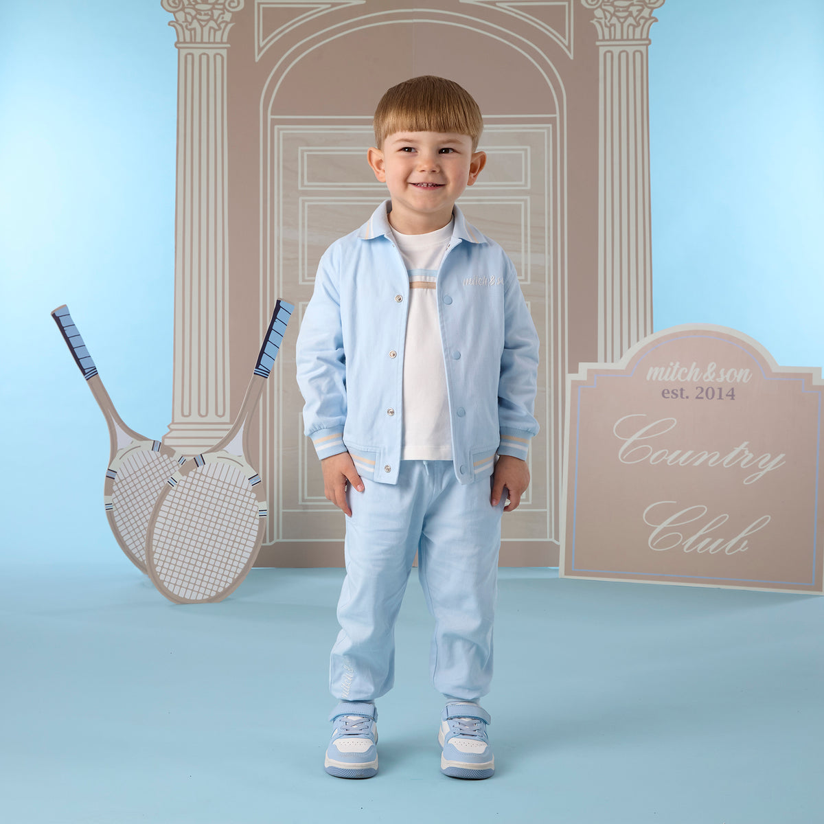 Jongen in 2-delige lichtblauwe bomberjack set van Mitch & Son met drukknopen en streepdetails, Country Club collectie