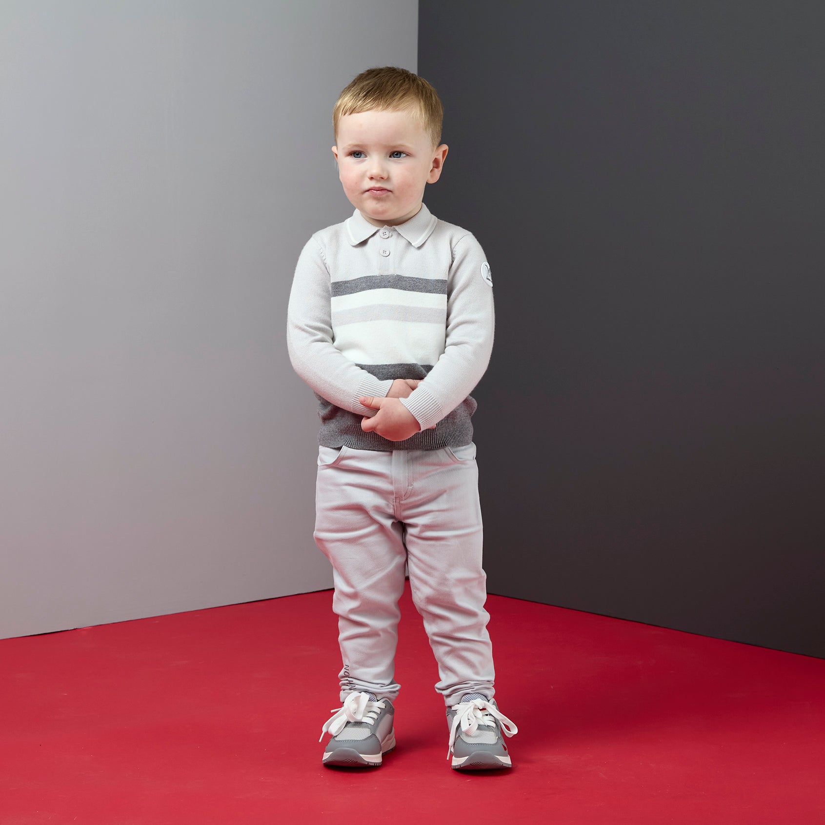 Peuter in lichtgrijze Mitch & Son Trace broek gecombineerd met gestreepte polo en sneakers